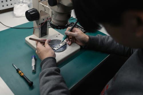 Technician repairing smartphone motherboard